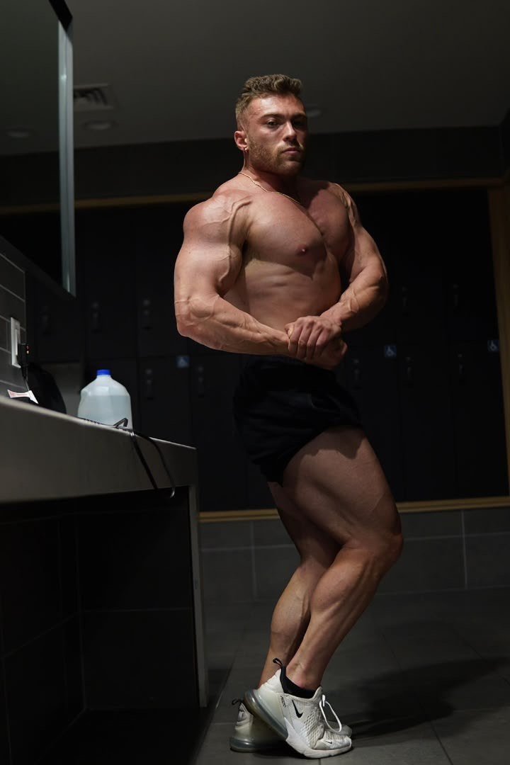 Athlete hitting a side chest pose in a locker room